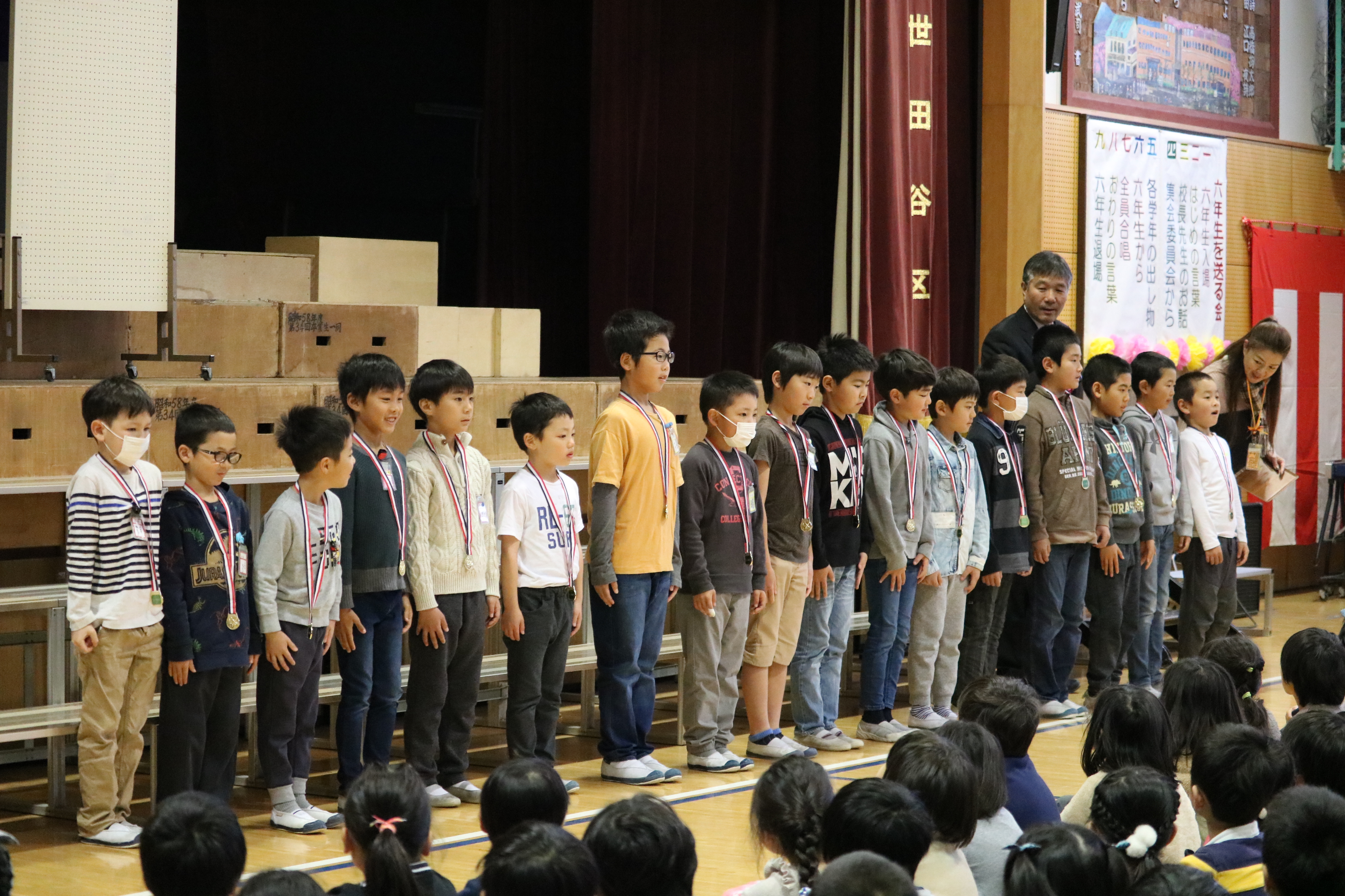小学校朝の会で全校生徒の前で表彰される選手たち